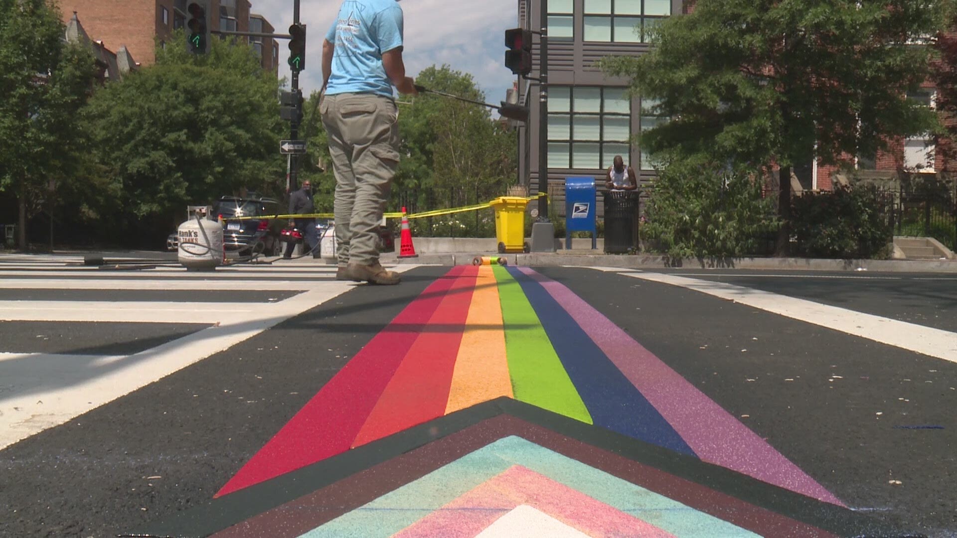 The crosswalk includes the colors of the Pride Flag, along with the Transgender Pride Flag colors and black and brown stripes to represent persons of color.